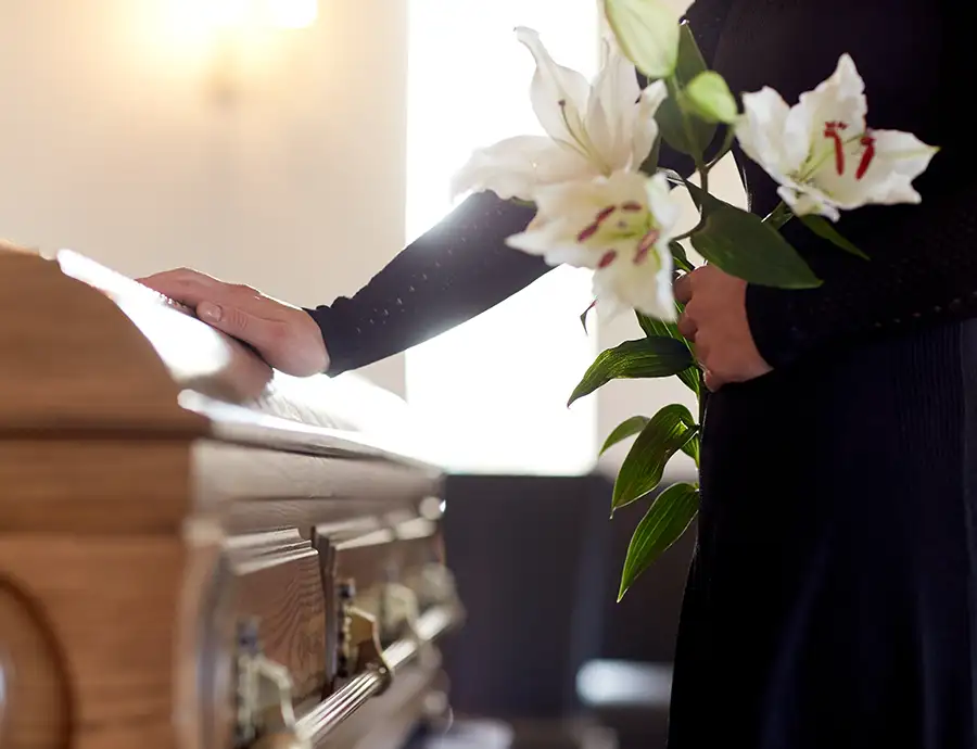 Wrongful Death - loss of a loved one due to negligence - grieving woman with hand on casket, lilies in the other hand - Jacksonville, IL
