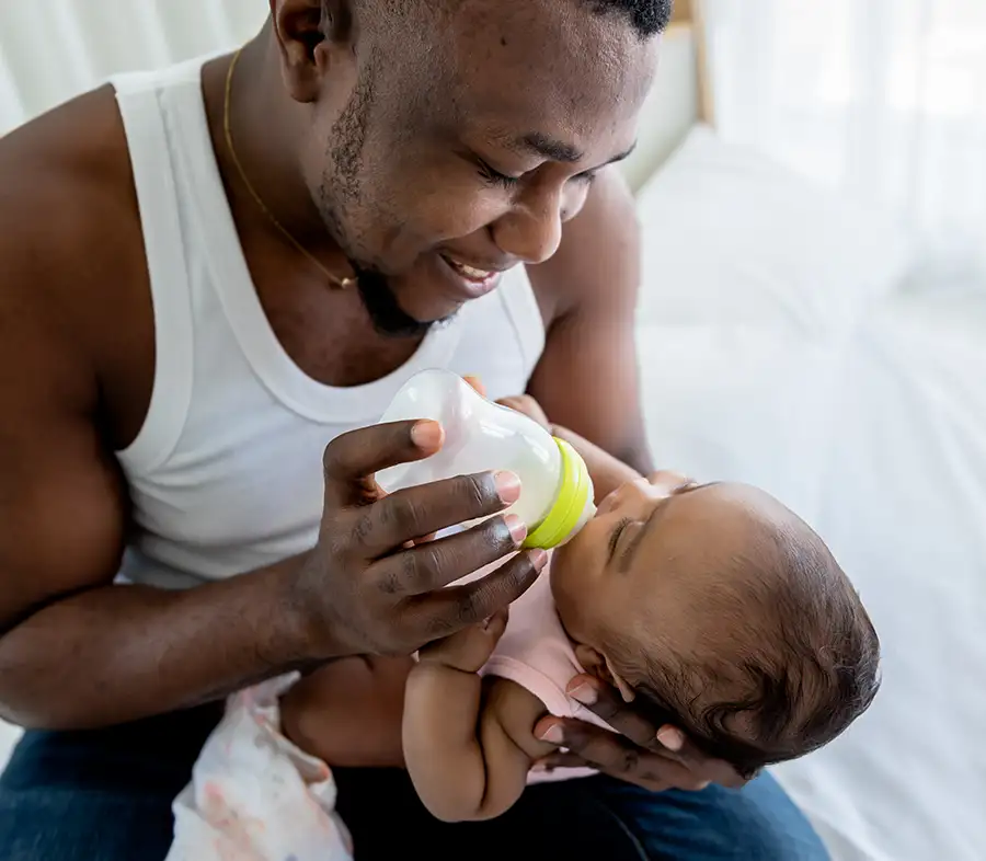 Paternity Law - Young African American father feeding his new born baby, responsible male parent taking care of child - Jacksonville, IL